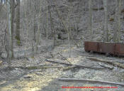 An old coal mine shaft that has been blasted closed.  The old coal rail cart and rail tracks still survive.