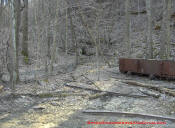 An old coal mine shaft that has been blasted closed.  The old coal rail cart and rail tracks still survive.